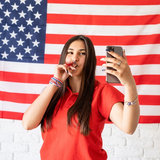 Bella donna che cattura un selfie sullo sfondo della bandiera USA