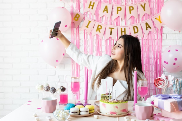 Bella donna che celebra la festa di compleanno prendendo selfie