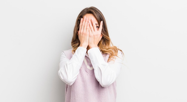 Bella donna che copre il viso con le mani che danno una occhiata tra le dita con espressione sorpresa e guardando di lato