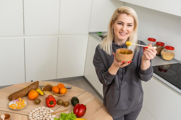 Bella donna che cucina e si diverte in cucina. Ragazza che cucina pasto sano con miele in cucina.