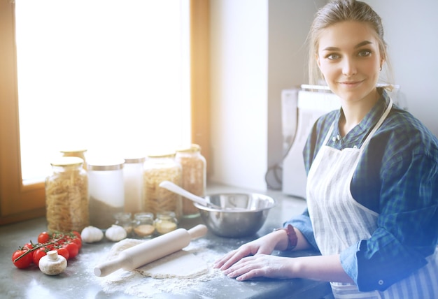 Bella donna che cucina la torta in cucina in piedi vicino alla scrivania