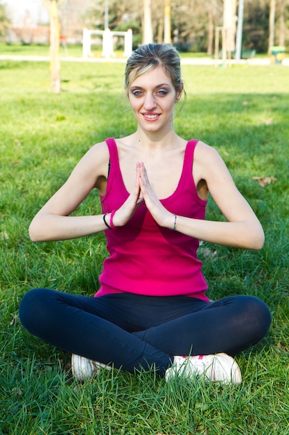 Bella donna che fa esercizi di yoga nel parco