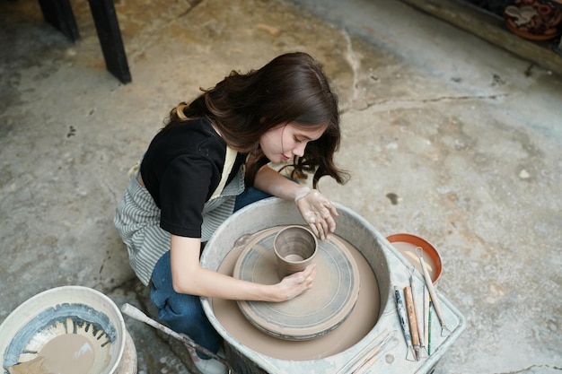 Bella donna che fa la ceramica sulla donna del primo piano delle mani della ruota nell'hobby di affari freelance