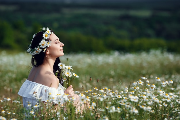 Bella donna che gode del campo, bella ragazza con i capelli scuri rilassante all'aperto, divertirsi, tenendo la pianta, felice giovane donna e natura verde primavera, concetto di armonia