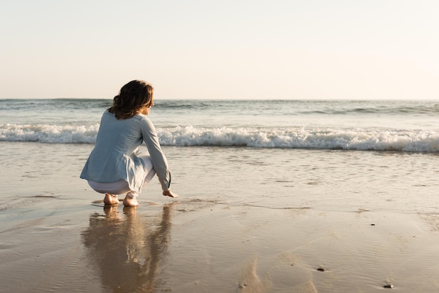 Bella donna che gode del tramonto sulla spiaggia