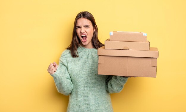 Bella donna che grida in modo aggressivo con un concetto di scatole di pacchetti di espressione arrabbiata