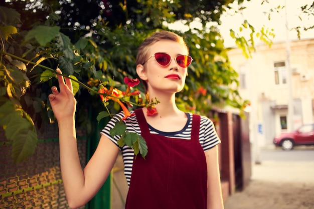 Bella donna che indossa occhiali da sole all'aperto moda posa fiori