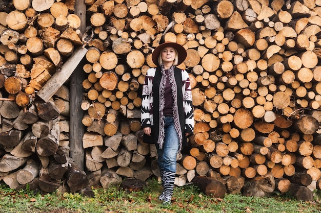 Bella donna che indossa un autentico cappello fatto a mano più dolce e marrone vicino al muro di legno tagliato