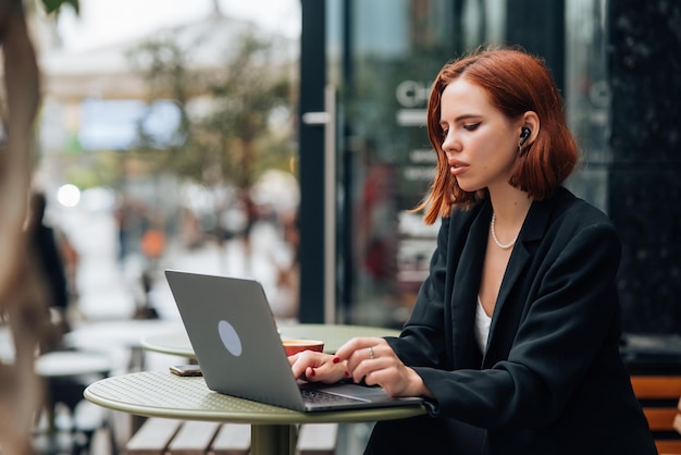 Bella donna che lavora al computer portatile al caffè all'aperto