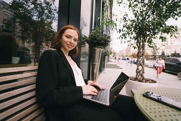 Bella donna che lavora al computer portatile al caffè all'aperto