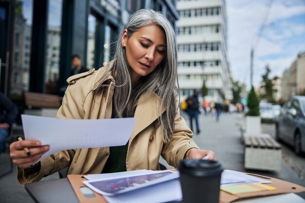 Bella donna che lavora con i documenti in un caffè all'aperto