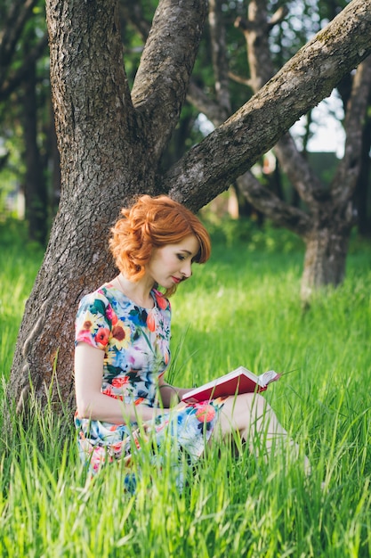 Bella donna che legge un giardino del libro in primavera
