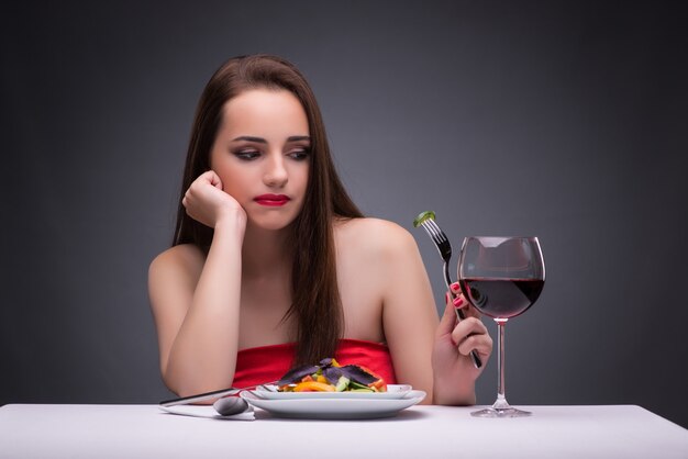 Bella donna che mangia da solo con il vino