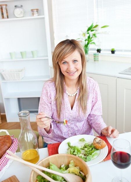 Bella donna che mangia insalata in cucina