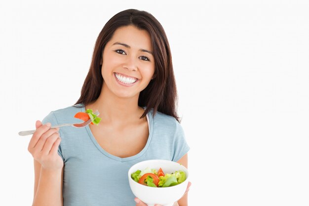 Bella donna che mangia una ciotola di insalata