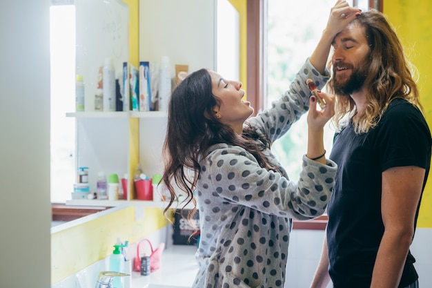 Bella donna che mette sulla crema idratante sul ragazzo nel bagno a casa