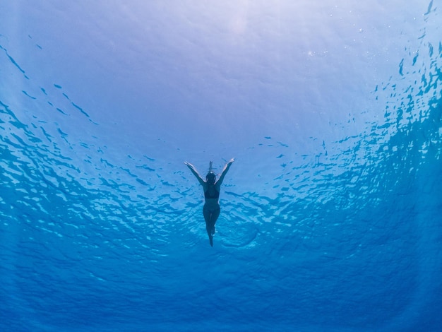 Bella donna che nuota sott'acqua con la maschera