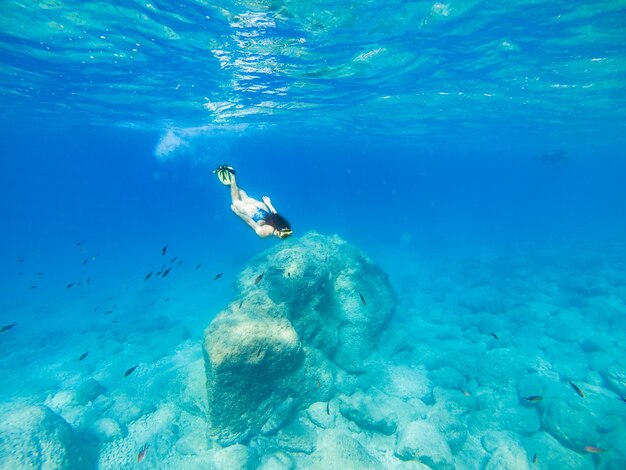 Bella donna che nuota sott'acqua con maschera per lo snorkeling e pinne