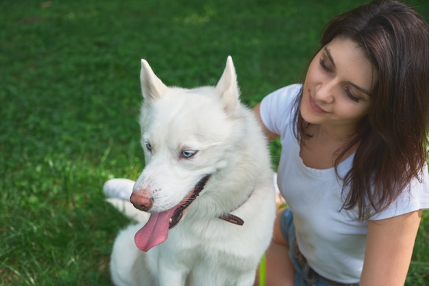 Bella donna che osserva al suo adorabile cane bianco con gli occhi azzurri
