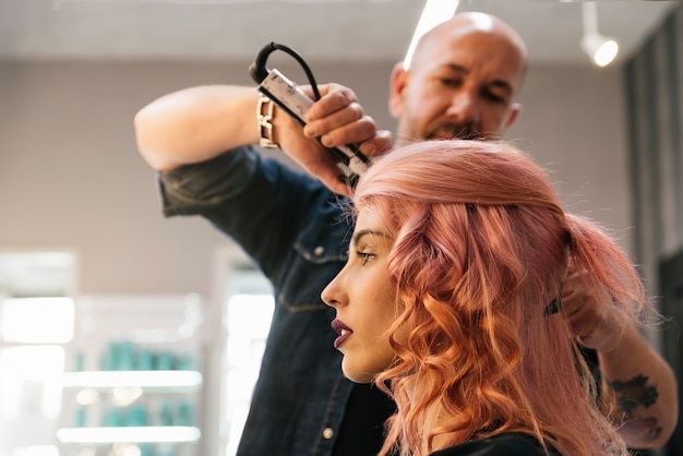 Bella donna che ottiene taglio di capelli dal parrucchiere nel salone di bellezza.