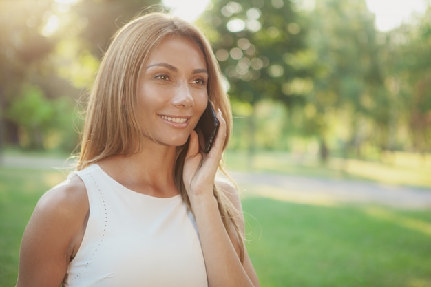 Bella donna che parla al telefono all'aperto