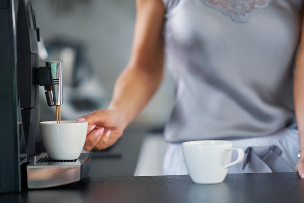 Bella donna che prepara il caffè in cucina