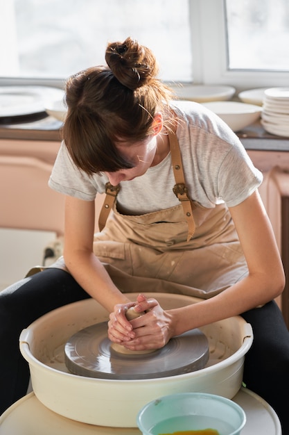 Bella donna che produce terraglie ceramiche sulla ruota, primo piano delle mani. Concetto per donna in freelance