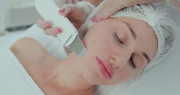 Bella donna che riceve il peeling e la pulizia del viso con cavitazione ad ultrasuoni. Cosmetologia e cura della pelle del viso. trattamento viso, pulizia viso.