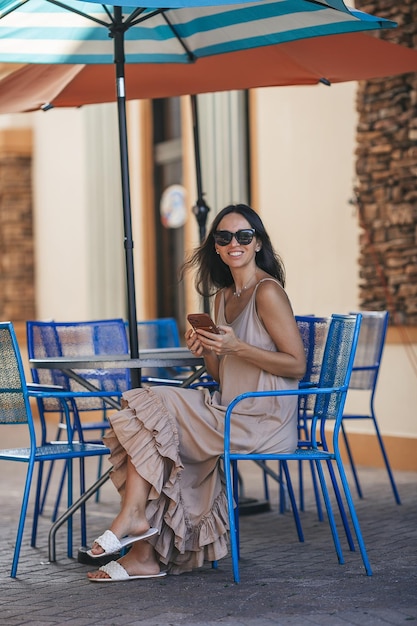 Bella donna che scrive un messaggio in un caffè estivo all'aperto