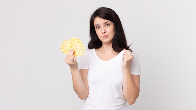 Bella donna che sembra arrogante positiva e orgogliosa e tiene in mano una dieta di torte di riso