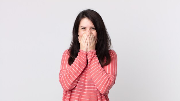 Bella donna che sembra felice, allegra, fortunata e sorpresa che copre la bocca con entrambe le mani