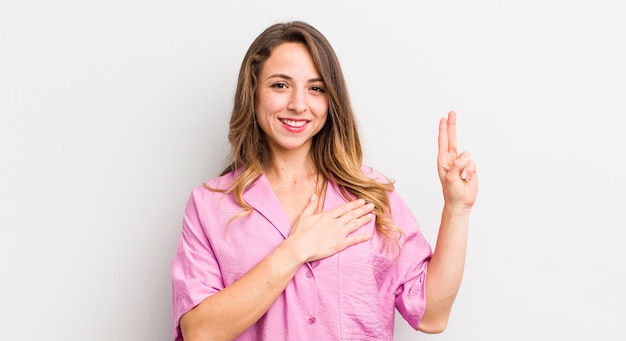 Bella donna che sembra felice, sicura di sé e degna di fiducia, sorridente e mostra il segno della vittoria con un atteggiamento positivo