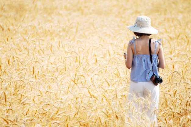 bella donna che si diverte a riprendere con la macchina fotografica nei campi di orzo