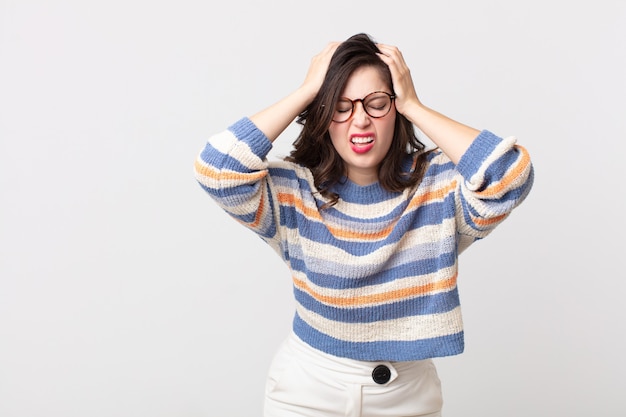 Bella donna che si sente stressata e frustrata, alza le mani alla testa, si sente stanca, infelice e con emicrania