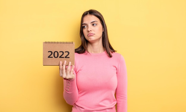 Bella donna che si sente triste o arrabbiata e guarda al concetto di calendario 2022 laterale