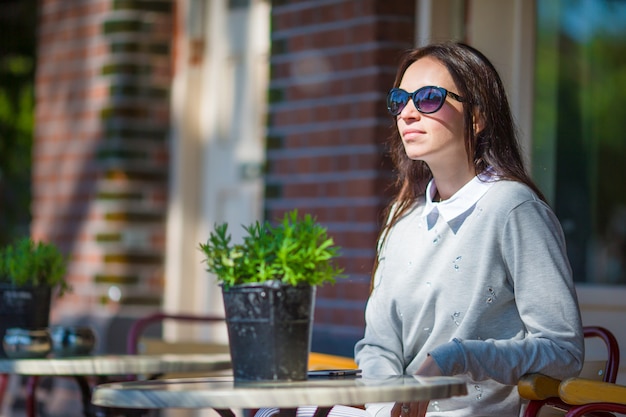 Bella donna che si siede in caffè all'aperto alla città europea