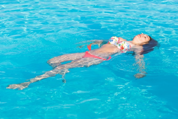 Bella donna che si trova sulla superficie dell&#39;acqua della piscina