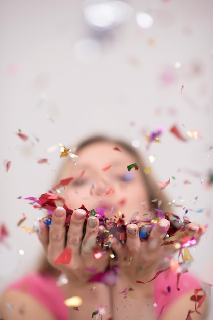 Bella donna che soffia coriandoli nell'aria festa di capodanno celebrazione isolata su sfondo bianco