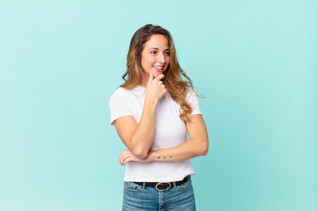 Bella donna che sorride con un'espressione felice e sicura con la mano sul mento