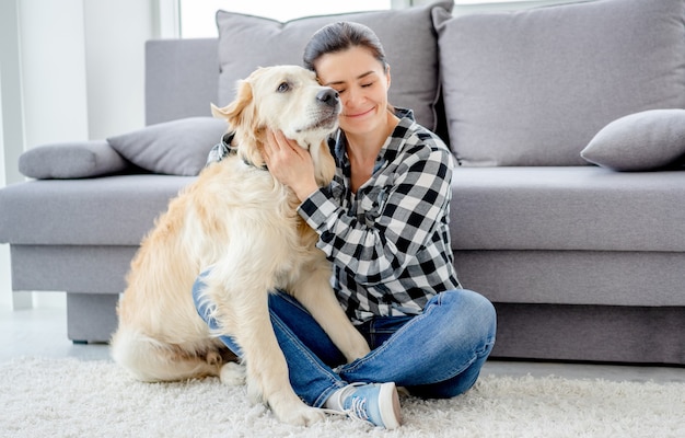 Bella donna che stringe a sé un bel cane in una stanza luminosa