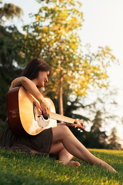 Bella donna che suona la chitarra nel parco.