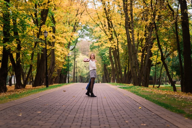 Bella donna che suona la chitarra ukulele all'aperto nella foresta autunnale