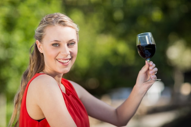 Bella donna che tiene bicchiere di vino nel parco