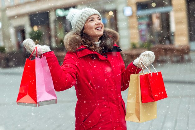 Bella donna che tiene i sacchetti della spesa in una giornata nevosa