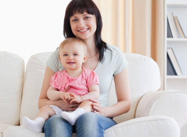 Bella donna che tiene il suo bambino tra le braccia mentre era seduto su un divano