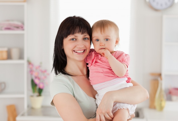 Bella donna che tiene il suo bambino tra le braccia mentre in piedi