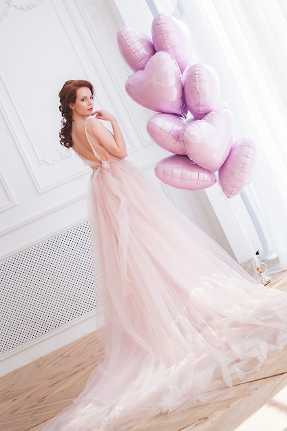 Bella donna che tiene palloncini rosa a forma di cuore. Modello femminile su st. Sfondo di San Valentino.