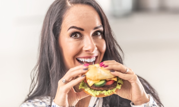 Bella donna che tiene un hamburger in mano con un sorriso.