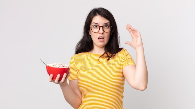 Bella donna che urla con le mani in alto e tiene in mano una ciotola per la colazione