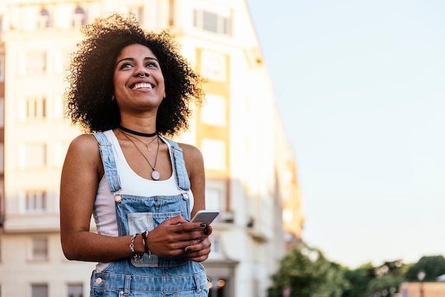 Bella donna che utilizza cellulare in strada. Concetto di gioventù.